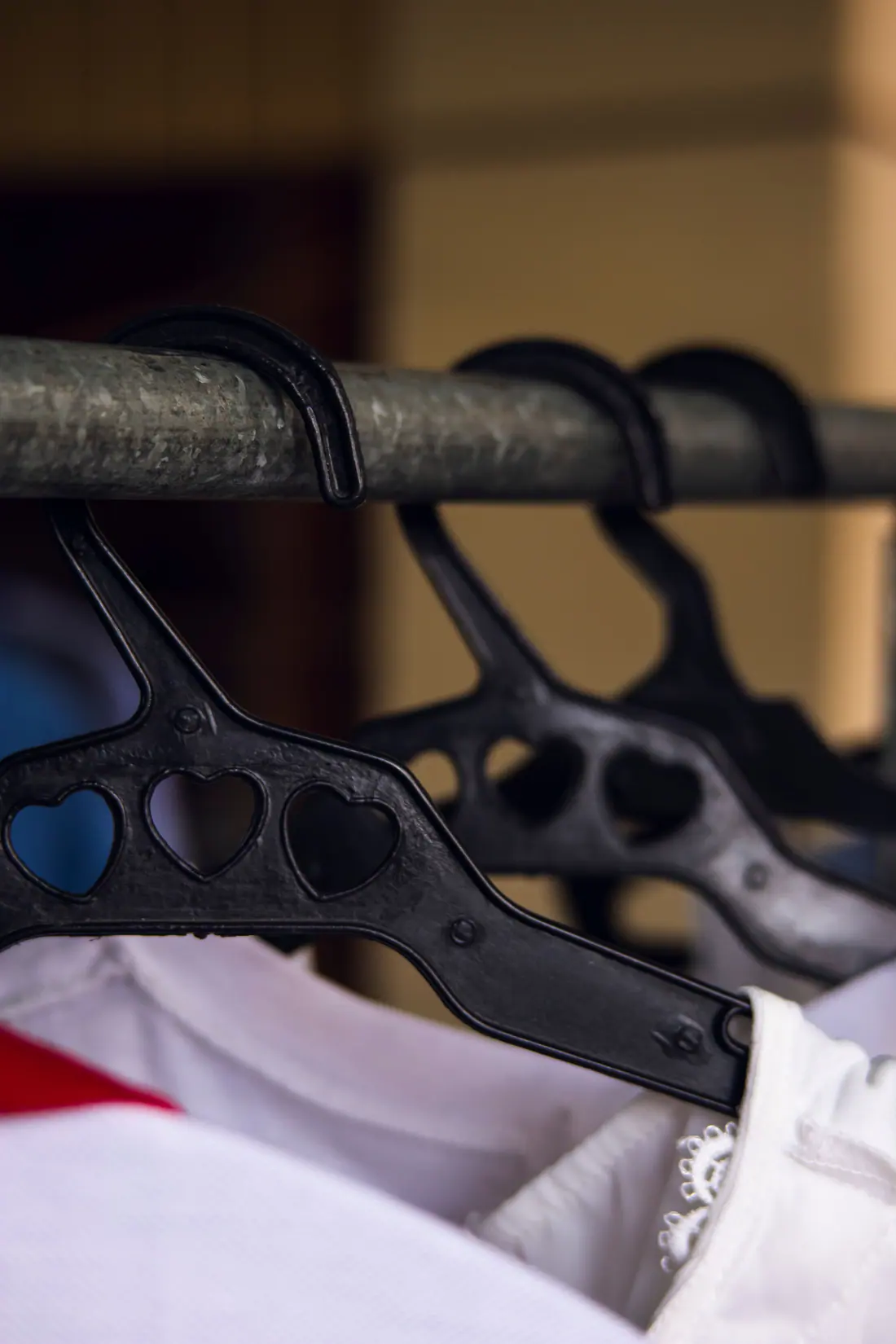 Black plastic hangers on a metal garment rail.